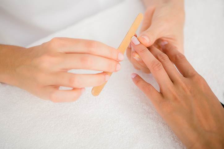 Beautician filing female clients nails at spa beauty salon