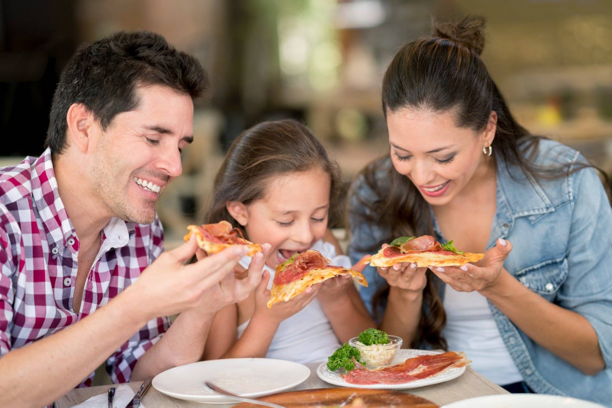 Happy family eating pizza at a restaurant